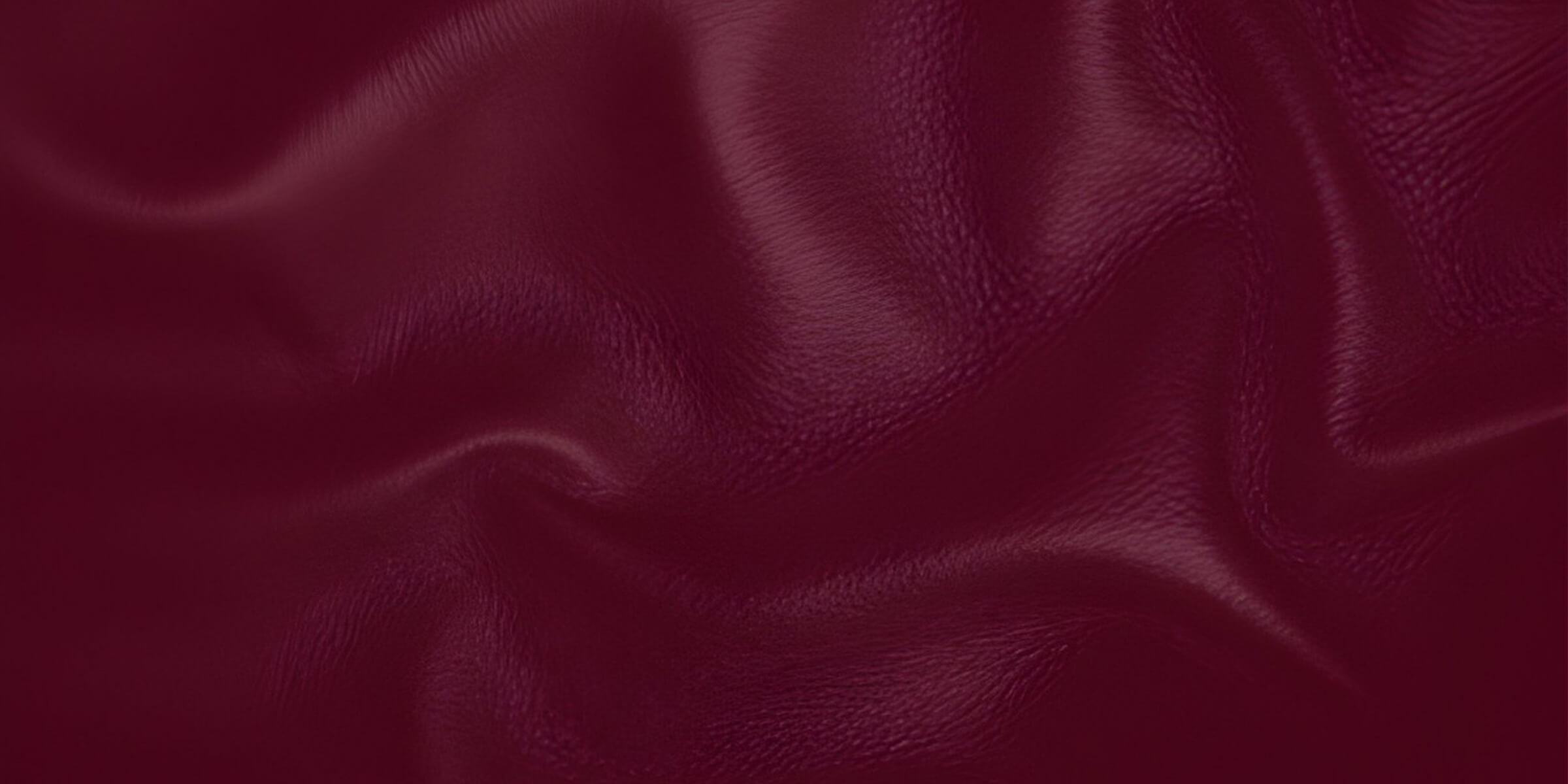 Close-up of deep wine-red leather draped in soft folds, catching the light.